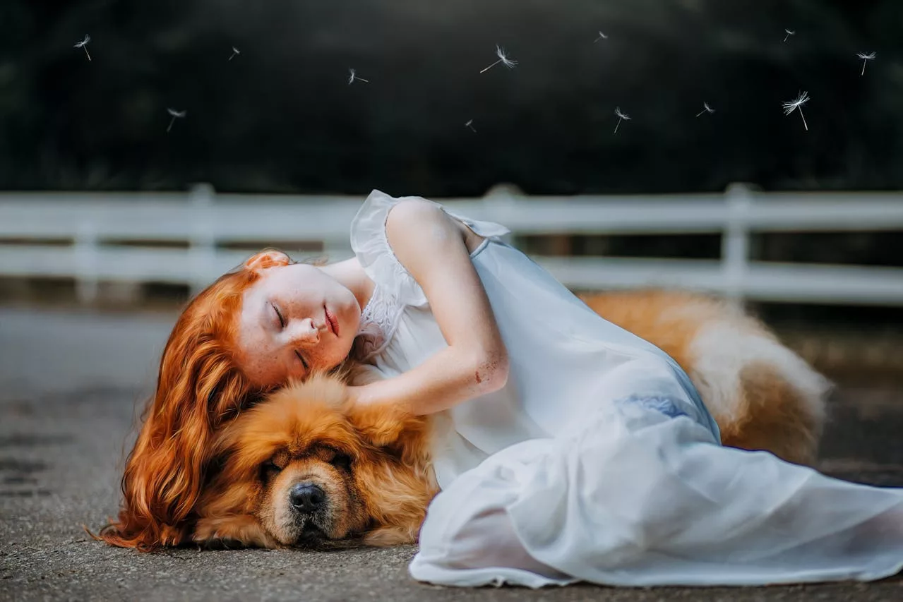 red-headed girl sleeping on top of a dog