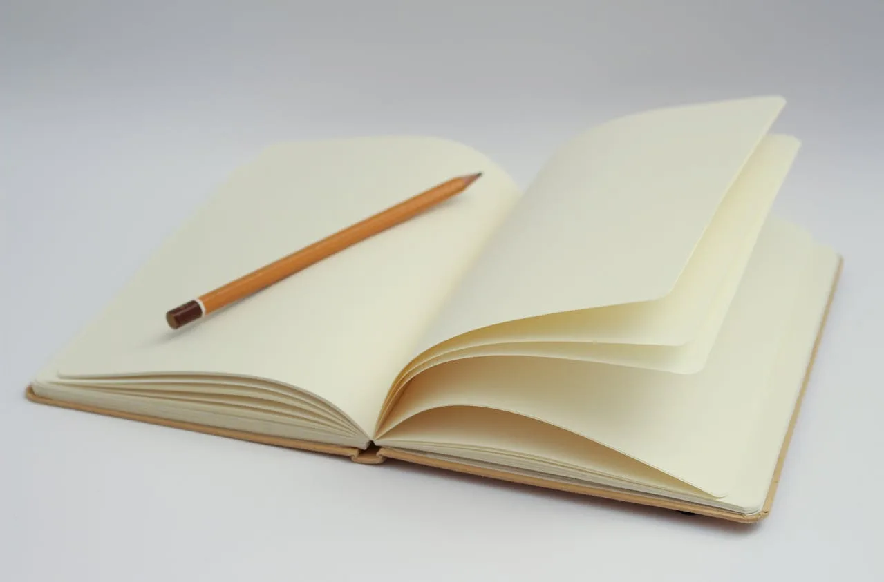 Picture of open blank notebook with a pencil inside, ready for novel planning - Photo by Dom J for Pexels